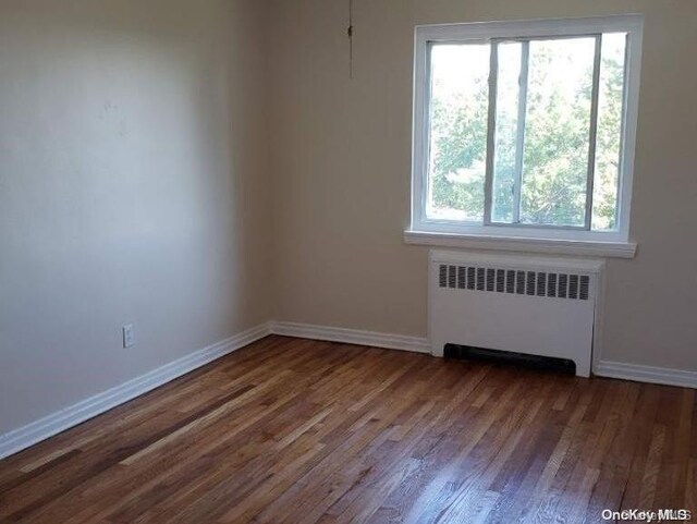 spare room featuring radiator heating unit and dark wood-type flooring