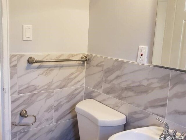 bathroom featuring sink, tile walls, and toilet