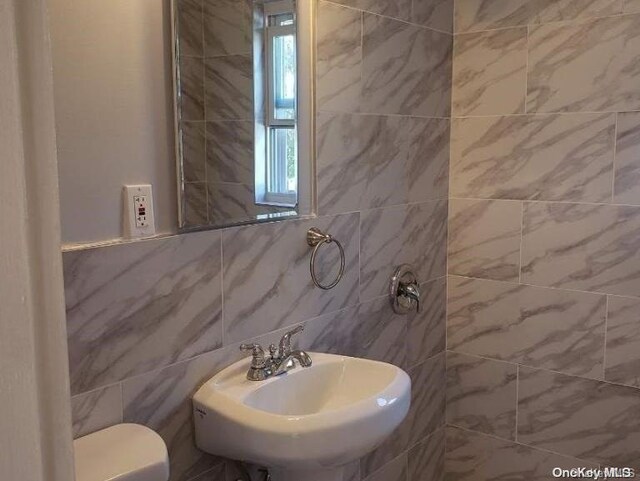 bathroom with sink, tile walls, and toilet