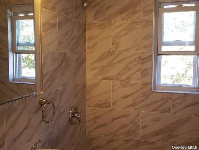 bathroom with tiled shower and plenty of natural light