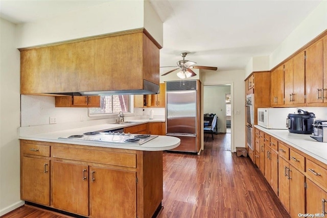 kitchen featuring kitchen peninsula, white appliances, ceiling fan, sink, and dark hardwood / wood-style floors