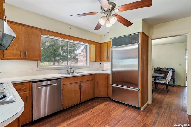 kitchen featuring ventilation hood, dark hardwood / wood-style flooring, sink, and appliances with stainless steel finishes