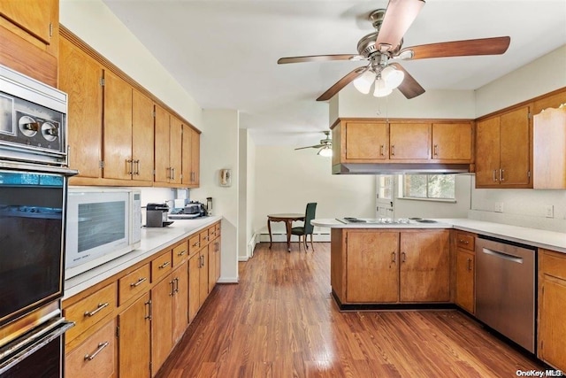 kitchen featuring kitchen peninsula, appliances with stainless steel finishes, a baseboard radiator, and dark wood-type flooring