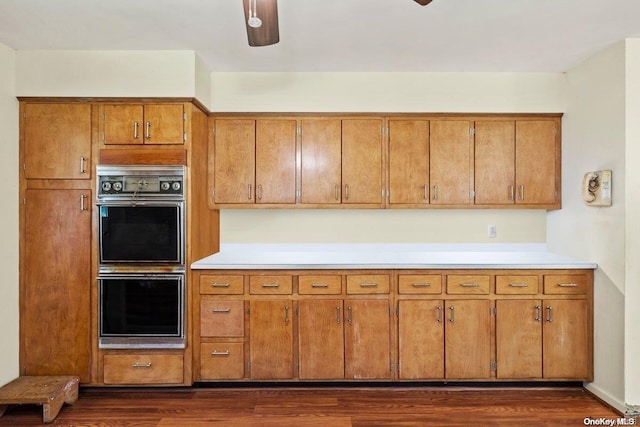 kitchen with black double oven, dark hardwood / wood-style floors, and ceiling fan