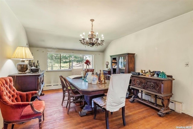 dining space featuring baseboard heating, hardwood / wood-style floors, a chandelier, and vaulted ceiling