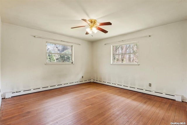 empty room featuring hardwood / wood-style flooring, a baseboard radiator, and ceiling fan