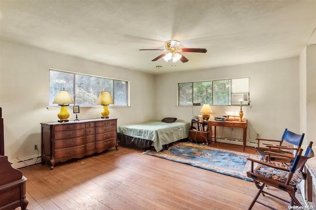 bedroom with baseboard heating, ceiling fan, and light hardwood / wood-style floors