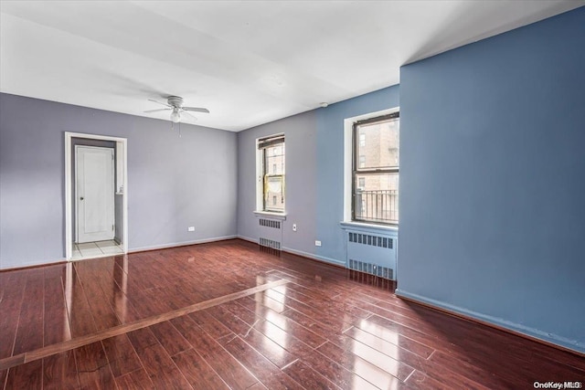 empty room with ceiling fan, radiator heating unit, and hardwood / wood-style flooring