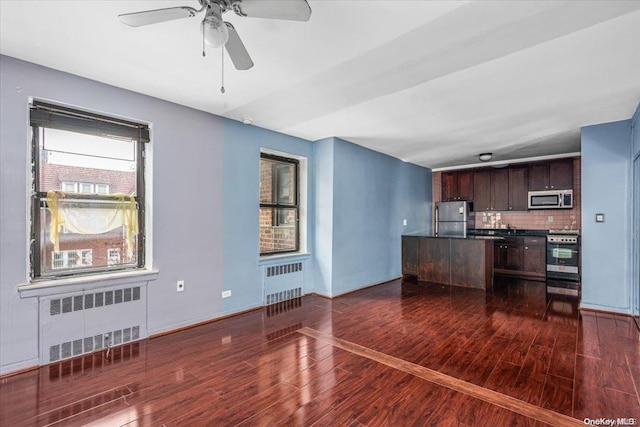 kitchen with appliances with stainless steel finishes, dark brown cabinetry, radiator, and tasteful backsplash