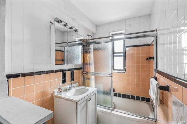 bathroom featuring shower / bath combination with glass door, vanity, and tile walls