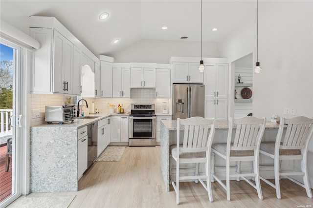 kitchen featuring stainless steel appliances, white cabinetry, hanging light fixtures, and light stone counters