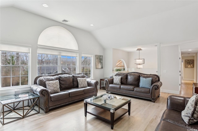 living room featuring high vaulted ceiling, light hardwood / wood-style flooring, and a healthy amount of sunlight