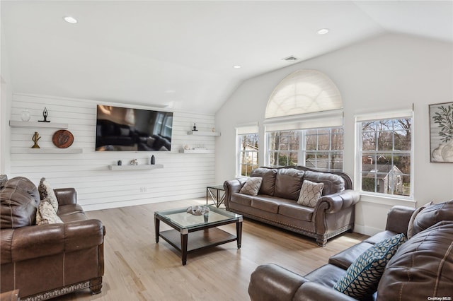 living room with wooden walls, lofted ceiling, and light wood-type flooring