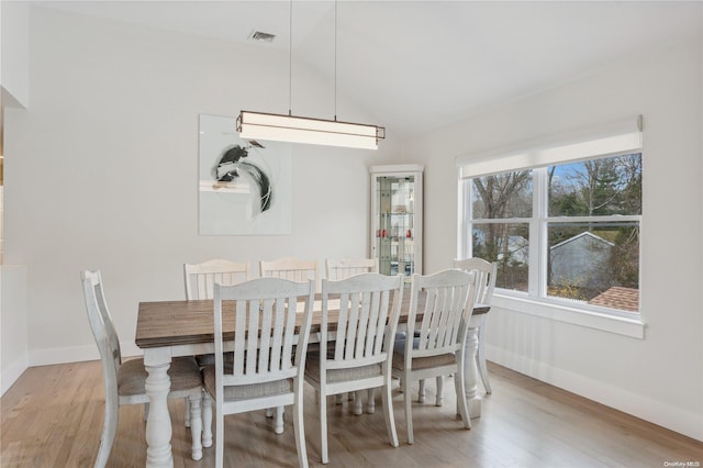 dining room with light wood-type flooring and vaulted ceiling