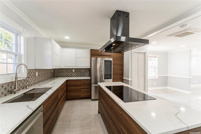 kitchen with sink, tasteful backsplash, island range hood, white cabinetry, and stainless steel appliances