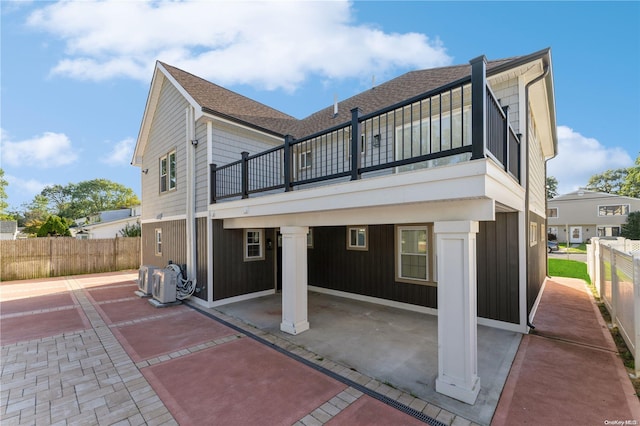 rear view of house with a patio area, a balcony, and ac unit