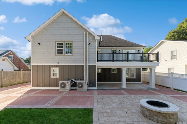 rear view of house featuring a patio area, a balcony, ac unit, and an outdoor fire pit