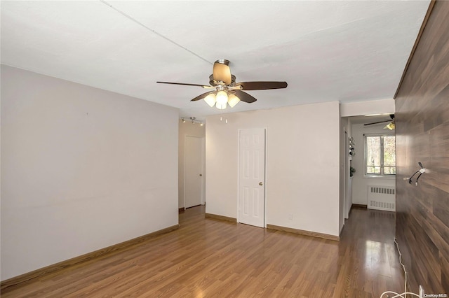 unfurnished room with hardwood / wood-style floors, ceiling fan, and radiator heating unit