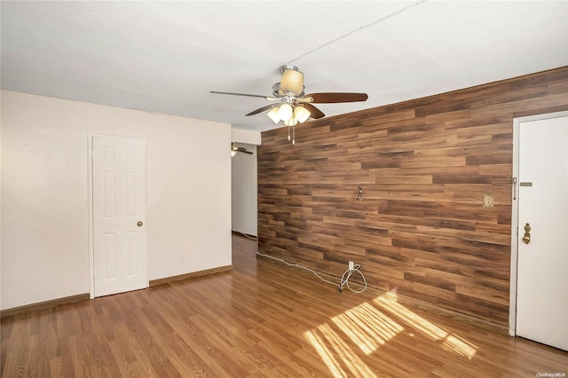 spare room with wood walls, ceiling fan, and wood-type flooring