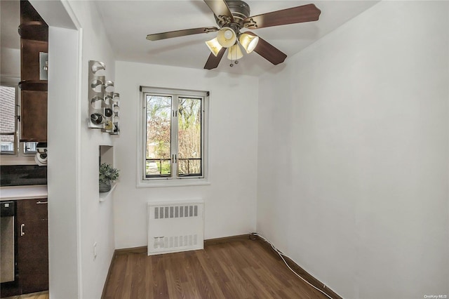 empty room with radiator heating unit, dark hardwood / wood-style flooring, and ceiling fan