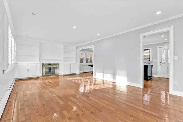 unfurnished living room with a wealth of natural light, a high end fireplace, light hardwood / wood-style floors, and a baseboard radiator