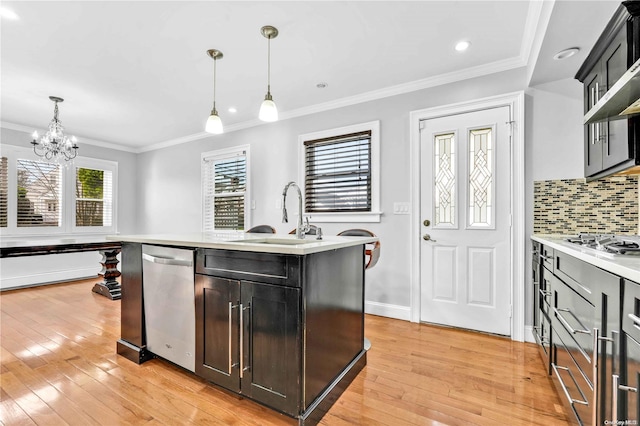 kitchen featuring sink, stainless steel appliances, hanging light fixtures, light hardwood / wood-style floors, and a center island with sink