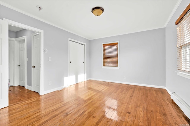 unfurnished bedroom featuring baseboard heating, ornamental molding, and light wood-type flooring