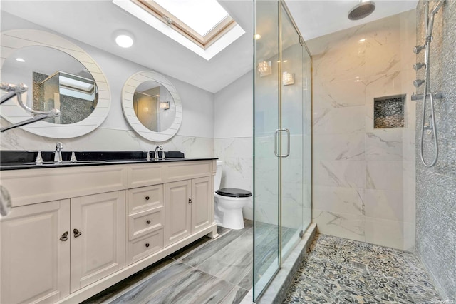 bathroom with vaulted ceiling with skylight, vanity, a shower with door, tile walls, and toilet