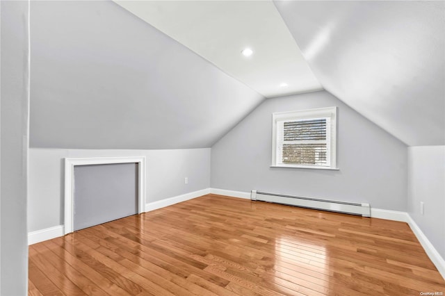 bonus room with light wood-type flooring, a baseboard radiator, and vaulted ceiling