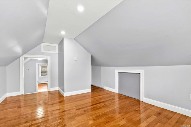 additional living space with light hardwood / wood-style flooring and lofted ceiling