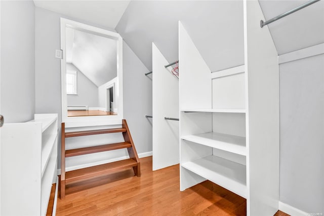 spacious closet featuring vaulted ceiling, light hardwood / wood-style flooring, and a baseboard heating unit