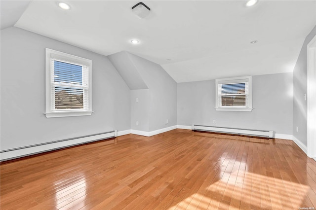 additional living space with a healthy amount of sunlight, light hardwood / wood-style floors, and baseboard heating