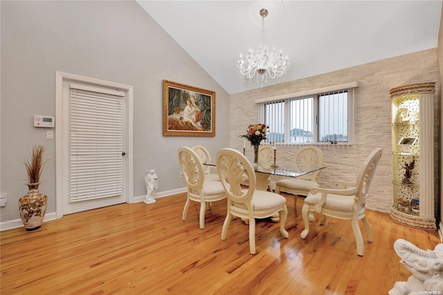 dining space with high vaulted ceiling, light hardwood / wood-style floors, and an inviting chandelier