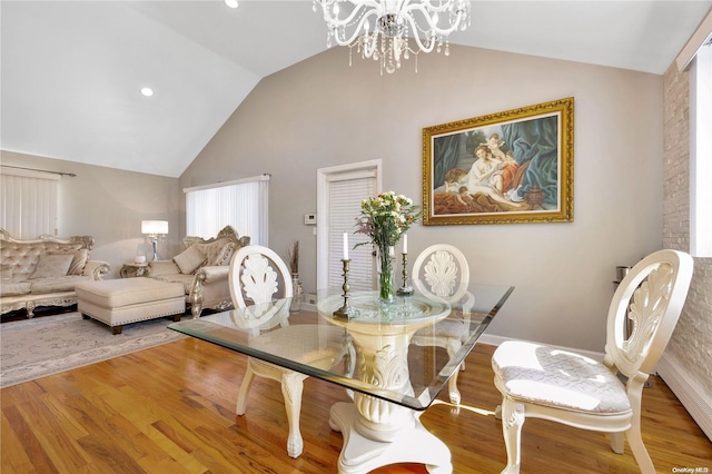 dining room with hardwood / wood-style floors, a chandelier, and vaulted ceiling