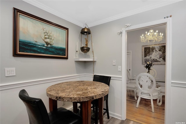 dining space with a chandelier, hardwood / wood-style flooring, and ornamental molding