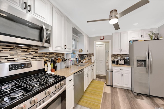 kitchen featuring white cabinets, crown molding, sink, light hardwood / wood-style flooring, and appliances with stainless steel finishes