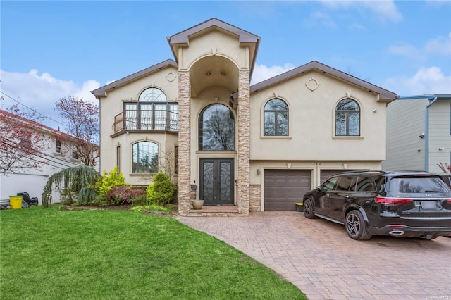 view of front of house featuring a front lawn, a garage, a balcony, and french doors