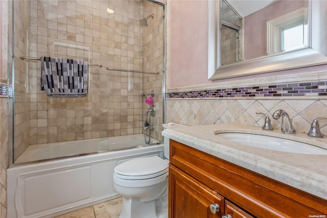 full bathroom featuring vanity, shower / bath combination with glass door, tile walls, tile patterned flooring, and toilet