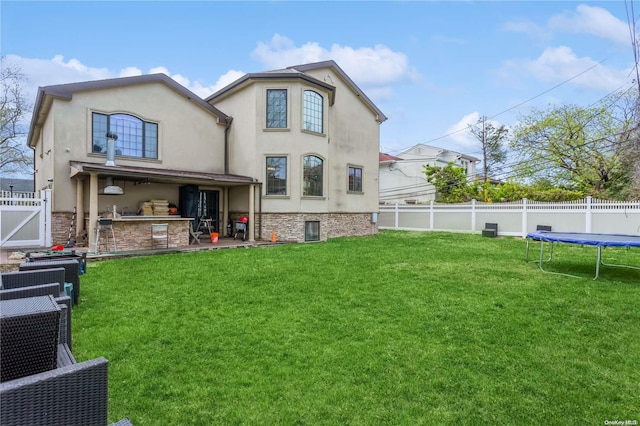 rear view of house featuring a lawn, a patio, and a trampoline