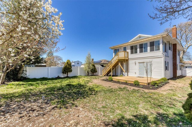 back of house featuring a lawn and a wooden deck