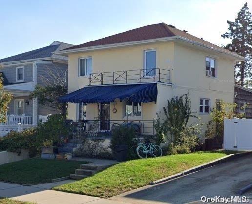 view of front of home featuring a balcony and a front yard