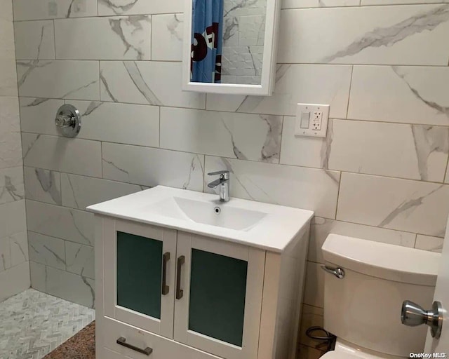 bathroom featuring vanity, toilet, a tile shower, and tile walls