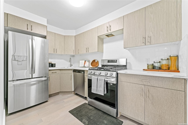 kitchen featuring decorative backsplash, light brown cabinetry, light wood-type flooring, and appliances with stainless steel finishes