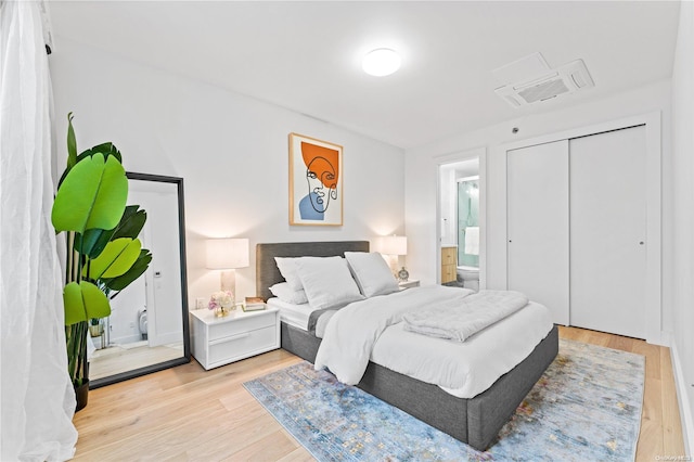 bedroom with ensuite bathroom, a closet, and light hardwood / wood-style flooring