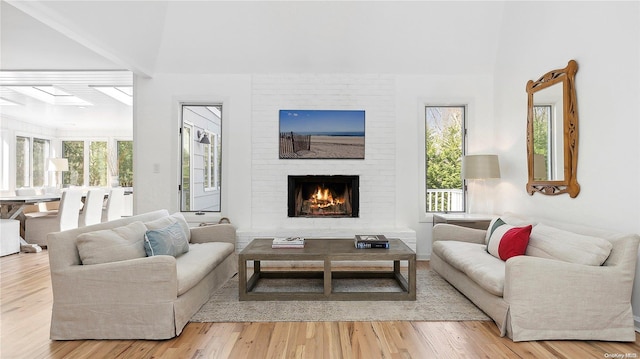 living room featuring a large fireplace, a healthy amount of sunlight, and light wood-type flooring