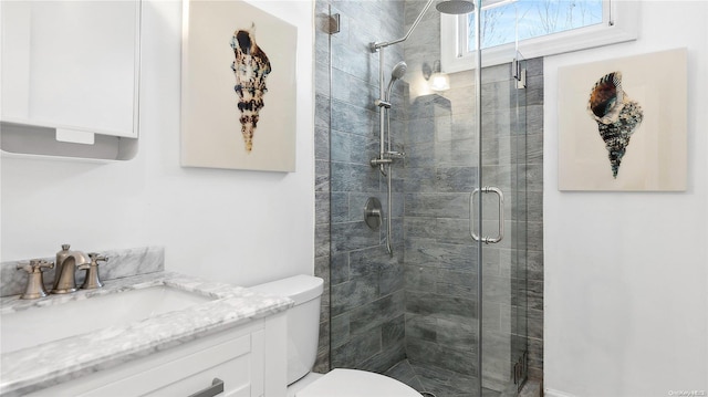 bathroom featuring a shower with door, vanity, and toilet