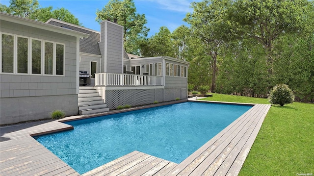 view of swimming pool with a lawn, a grill, and a deck