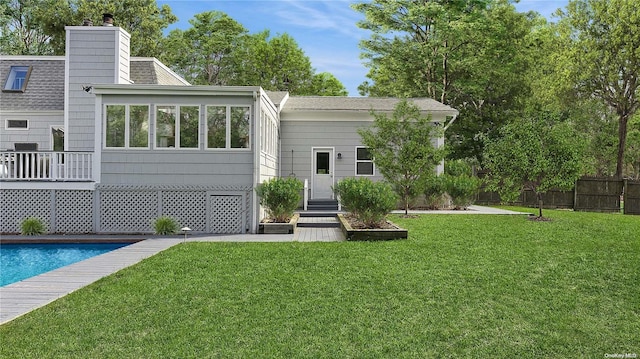 back of house featuring a pool side deck and a yard