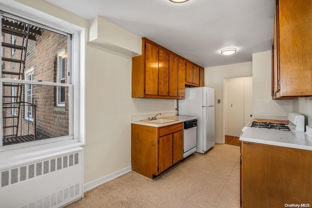 kitchen featuring radiator heating unit, white appliances, and sink