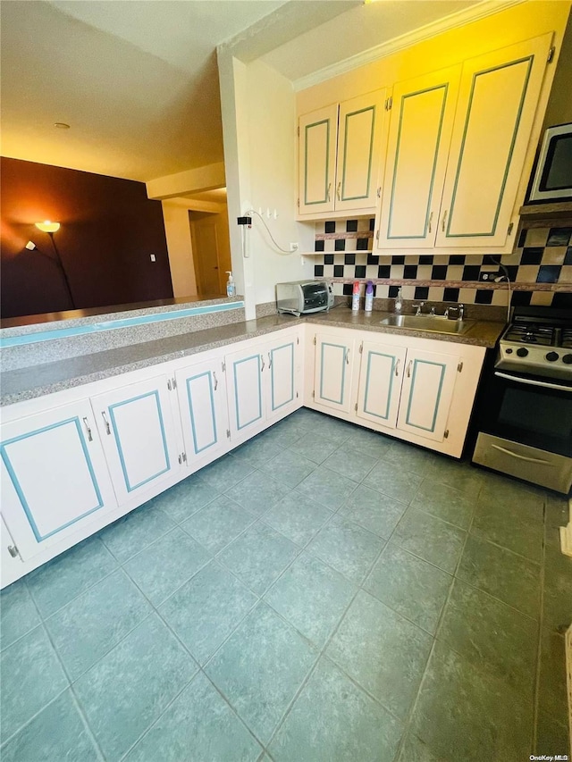 kitchen with backsplash, stove, white cabinets, and sink